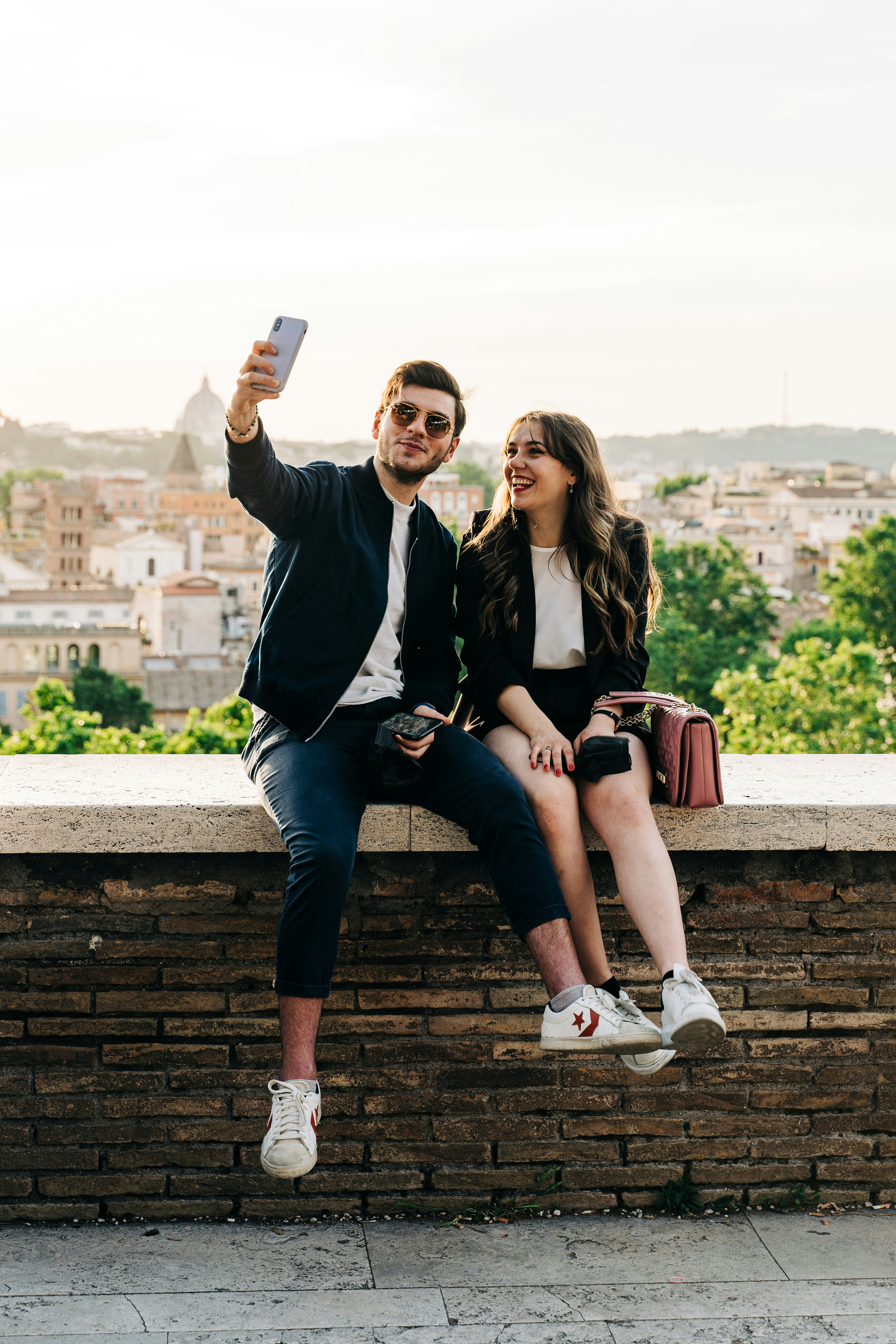 Couple taking a selfie on a brick wall
